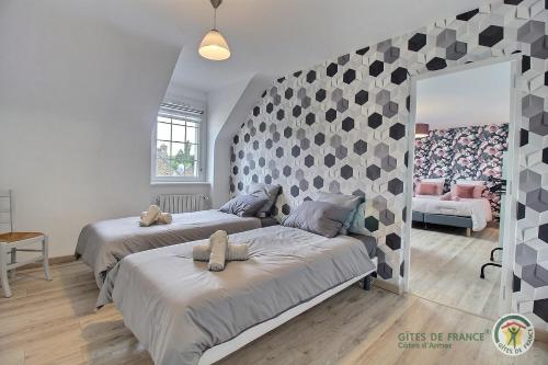 a bedroom with two beds and a wall with a mirror at Maison de la ville-j in Plénée-Jugon