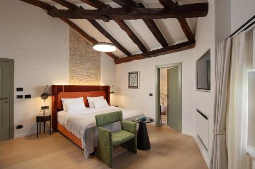 a bedroom with a bed and a green chair at Boutique Hotel San Rocco in Brtonigla