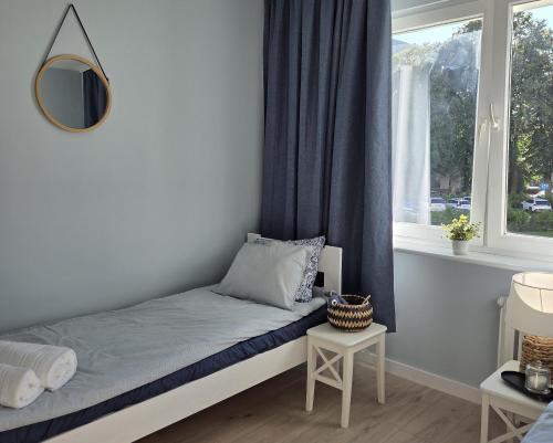 a small bedroom with a bed and a window at Morski Spokój Kołobrzeg apartment in Kołobrzeg