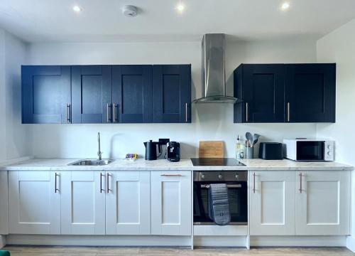 a kitchen with white cabinets and black appliances at Luxury Norwich City Centre Apartment - Free Parking in Norwich