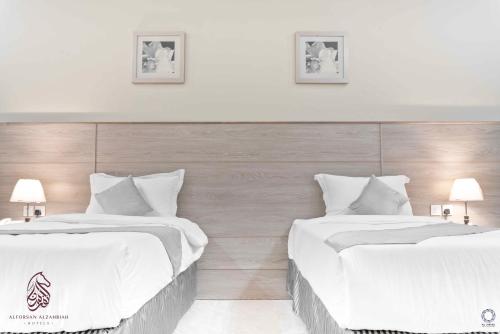 two beds in a hotel room with white sheets at SAHARI ALFORSAN HOTEL Sabya فندق صحاري الفرسان in Şabyā