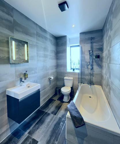 a bathroom with a tub and a sink and a toilet at Luxury Norwich City Centre Apartment - Free Parking in Norwich