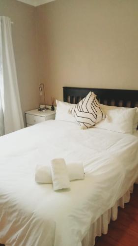 a large white bed with two white towels on it at Thee House - Mkamba Gardens in Pietermaritzburg