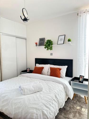 a white bedroom with a large bed with orange pillows at Dream Nook - One Bedroom Apt in Tatu City in Tatu City