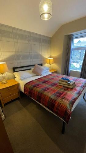 a bedroom with a bed with a plaid blanket at Autumn Leaves Guest House in Windermere