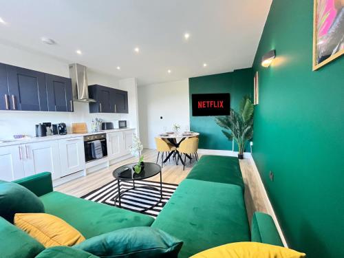 a living room with a green couch and a kitchen at Luxury Norwich City Centre Apartment - Free Parking in Norwich