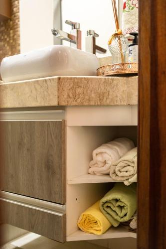 a bathroom with a sink and towels on a shelf at Apto Aconchegante Na Cidade do Café in Brejetuba