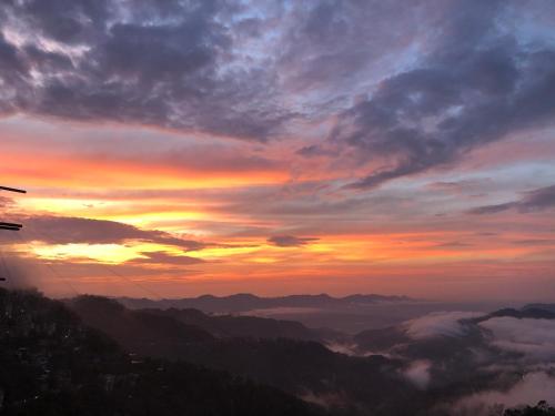 Una puesta de sol en las montañas con nubes en el valle. en W-26 Dawrpui, en Āīzawl