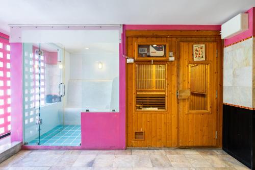 a bathroom with a wooden door and a walk in shower at Bella Villa Metro in Pattaya North