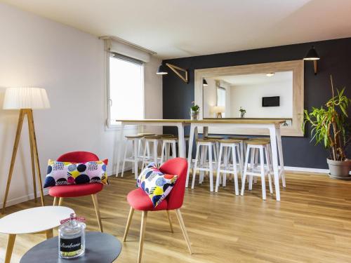 a living room with red chairs and a table at Aparthotel Adagio Access Strasbourg Illkirch in Illkirch-Graffenstaden