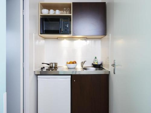 a small kitchen with a sink and a microwave at Aparthotel Adagio Access Strasbourg Illkirch in Illkirch-Graffenstaden
