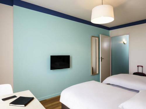 a room with two beds and a tv on the wall at Aparthotel Adagio Access Strasbourg Illkirch in Illkirch-Graffenstaden