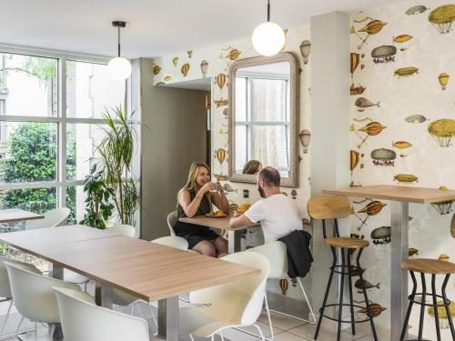 a man and woman sitting at a table in a restaurant at Aparthotel Adagio Access Nantes Viarme in Nantes