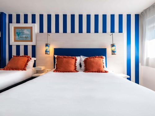 a bedroom with a large bed with blue and white stripes at ibis Styles Quiberon Centre in Quiberon