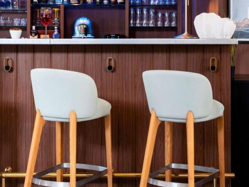 two white chairs sitting at a bar at ibis Styles Quiberon Centre in Quiberon