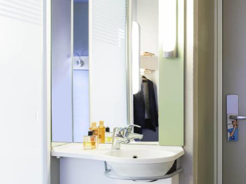 a bathroom with a sink and a mirror at ibis budget Zurich Airport in Glattbrugg
