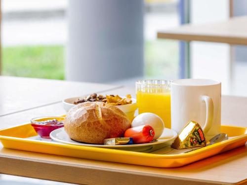 a tray with a plate of food and a cup of orange juice at ibis budget Zurich Airport in Glattbrugg