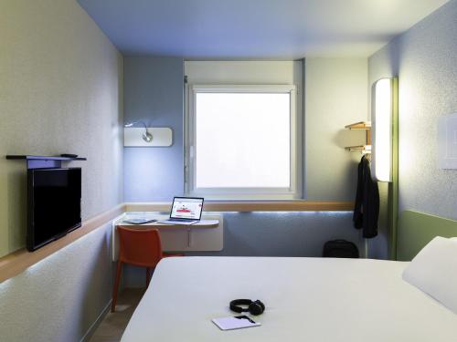 a room with a bed and a laptop on a desk at ibis budget Zurich Airport in Glattbrugg