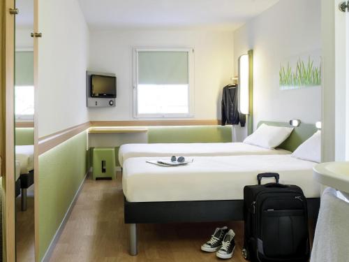 a hotel room with a bed and a suitcase at ibis budget Zurich Airport in Glattbrugg
