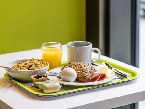 a tray of breakfast foods and a cup of orange juice at ibis budget Zurich Airport in Glattbrugg