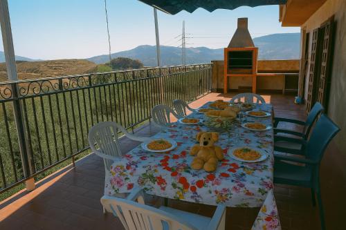 a teddy bear sitting at a table with plates of food at Casa Rural Chalet Venta del Aire Cortijo Terron in Lanjarón