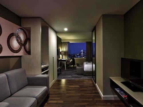 a living room with a couch and a television at Mercure Serpong Alam Sutera in Serpong