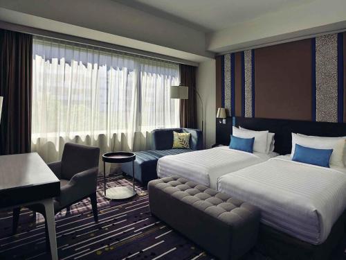 a hotel room with two beds and a desk at Mercure Serpong Alam Sutera in Serpong
