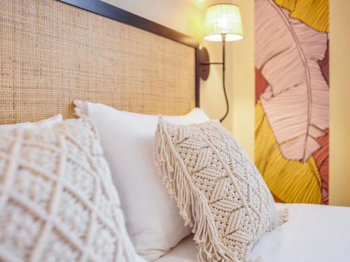 a bed with white pillows and a head board at Ibis Styles Nantes Centre Place Graslin in Nantes