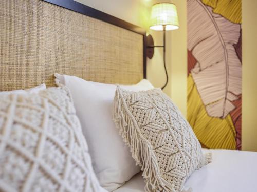 a bed with white pillows and a headboard with a lamp at Ibis Styles Nantes Centre Place Graslin in Nantes
