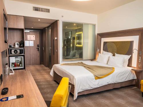 a hotel room with a large bed and a table at Novotel Sofia in Sofia