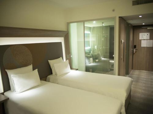 two beds in a hotel room with a mirror at Novotel Sofia in Sofia