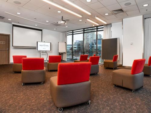 a meeting room with red chairs and a white screen at Novotel Sofia in Sofia