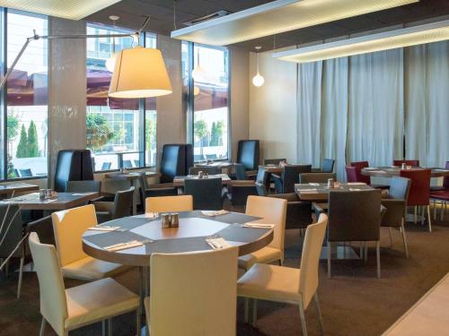 a dining room with tables and chairs and windows at Novotel Sofia in Sofia