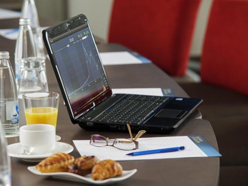 a laptop computer sitting on a table with a plate of pastries at Novotel Sofia in Sofia