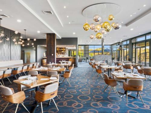 a restaurant with tables and chairs and windows at Mercure Kooindah Waters Central Coast in Wyong