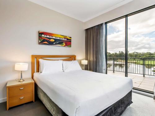 a bedroom with a bed and a large window at Mercure Kooindah Waters Central Coast in Wyong