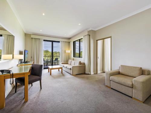 a large living room with a desk and chairs at Mercure Kooindah Waters Central Coast in Wyong