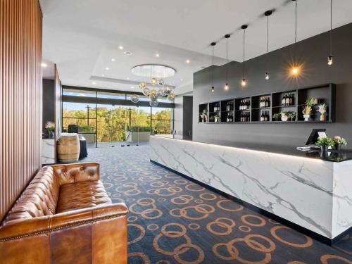 a lobby with a bar with a couch in the middle at Mercure Kooindah Waters Central Coast in Wyong