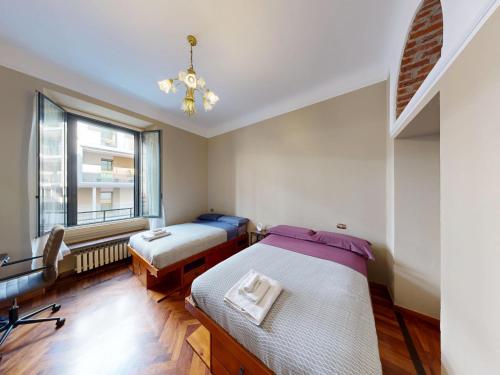 een slaapkamer met twee bedden en een raam bij Wonderful downtown apartment-HD NETFLIX, KING-SIZE BED, two minutes' walk from metro in Milaan