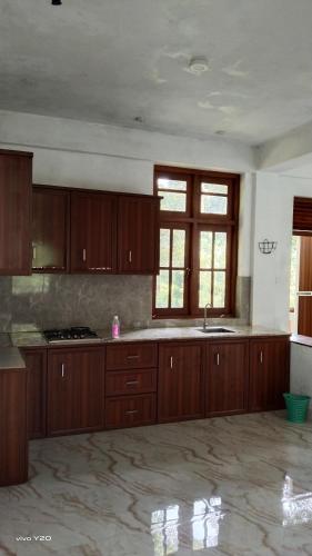 an empty kitchen with wooden cabinets and a sink at River way in Ratnapura