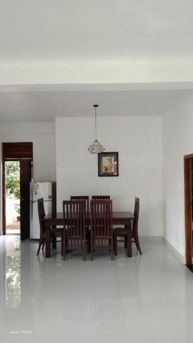 a dining room with a table and chairs and a refrigerator at River way in Ratnapura