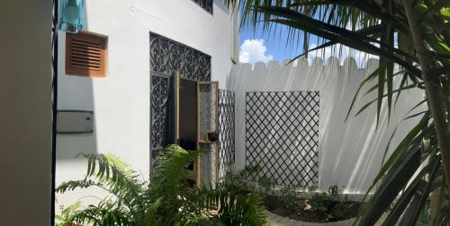 a white fence in front of a house with plants at Dhow House in Bagamoyo