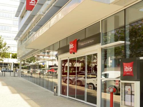 a building with a car reflection in the windows at Hotel Ibis Lisboa Parque das Nações in Lisbon