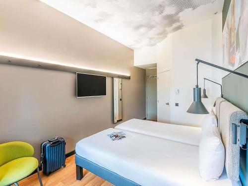 a room with a bed and a tv and a chair at Hotel Ibis Lisboa Parque das Nações in Lisbon