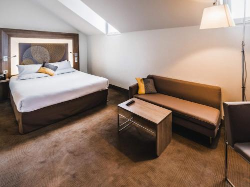 a hotel room with a bed and a couch at Novotel Toulouse Centre Wilson in Toulouse