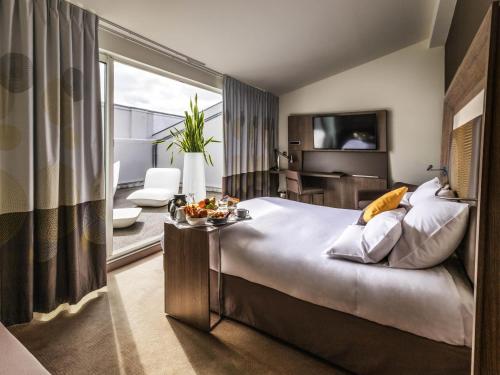 a hotel room with a large bed and a living room at Novotel Toulouse Centre Wilson in Toulouse