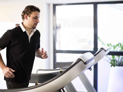 a man running on a treadmill in a gym at Novotel Toulouse Centre Wilson in Toulouse
