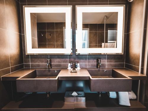 a bathroom with two sinks and two mirrors at Novotel Toulouse Centre Wilson in Toulouse