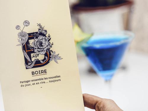 a hand holding a card with a blue drink at Novotel Toulouse Centre Wilson in Toulouse