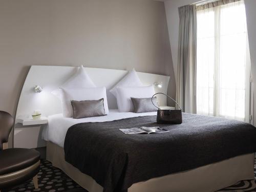 a bedroom with a large bed and a chair at Mercure Paris Levallois in Levallois-Perret